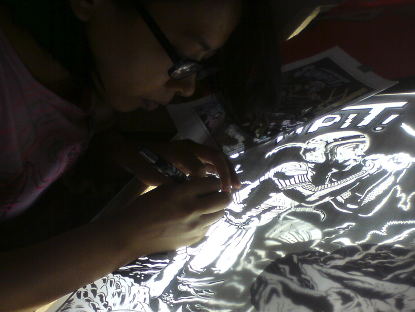 Examining details over the lightbox for one of JP Cuison's posters.